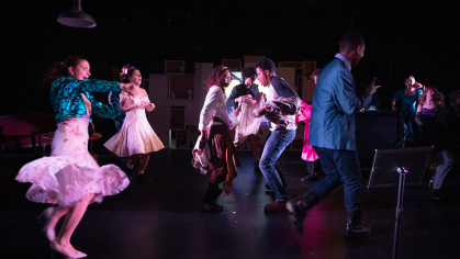 Rutgers student actors on stage dance around in a dark setting.