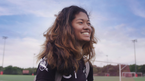 A smiling student on a soccer field