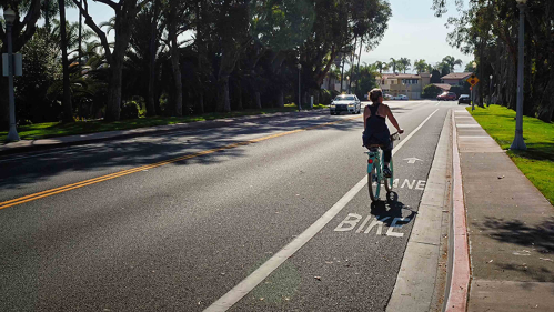 Bike rider to right of road in bike lane