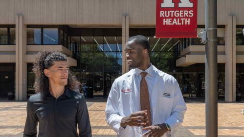 Martial arts instructor Michael Loureiro (left) and Rutgers medical student Yvan Yomba walk and talk outside of New Jersey Medical School in Newark.