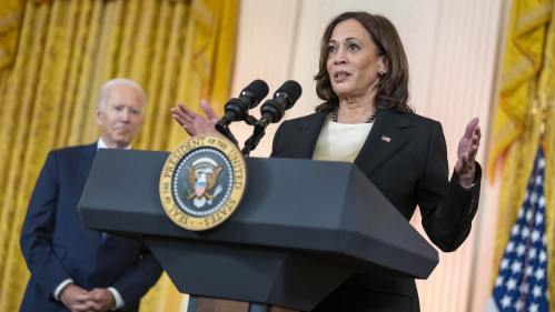 Vice President Kamala Harris at the White House podium as President Joe Biden looks on.