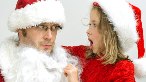 Child pulls down Santa's fake beard.