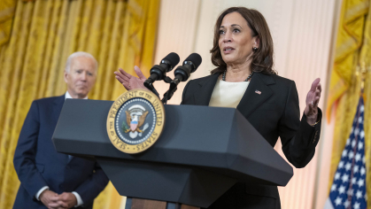 Vice President Kamala Harris at the White House podium as President Joe Biden looks on.