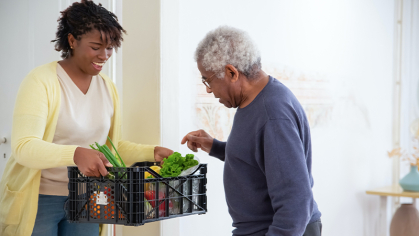 Women offering fresh vegetables to an older man