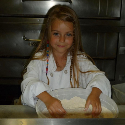 Little girl with her hands in a bowl of flour