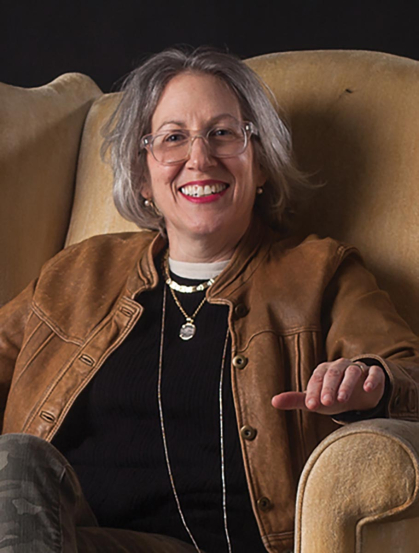 Rutgers art professor Julie Langsam sits in a big chair and smiles.