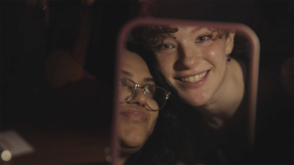 A still from "His New Girl" features a mirror reflection of actors Ashavari Bhattacharya (left) and Meg Moynahan.